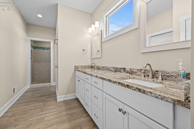 bathroom featuring visible vents, a stall shower, wood finished floors, and a sink