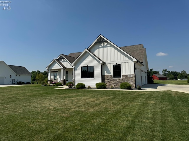 view of front of property featuring a front yard, driveway, an attached garage, stone siding, and board and batten siding