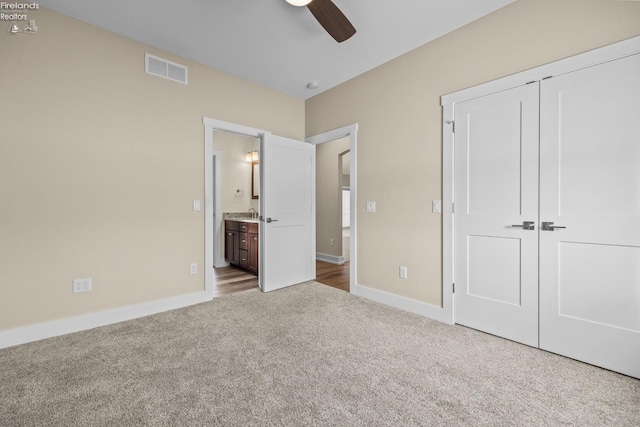 unfurnished bedroom with baseboards, visible vents, ensuite bath, a closet, and carpet flooring