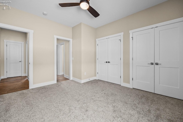 unfurnished bedroom featuring baseboards, multiple closets, a ceiling fan, and carpet flooring