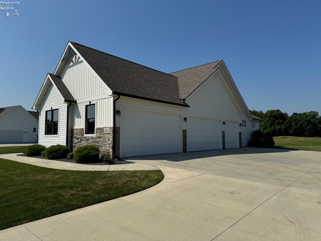 view of front of home with driveway, roof with shingles, a front lawn, a garage, and board and batten siding