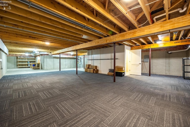 unfinished basement featuring brick wall and carpet floors