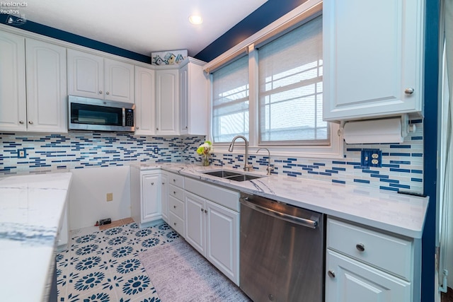 kitchen with white cabinets, light stone counters, stainless steel appliances, and sink