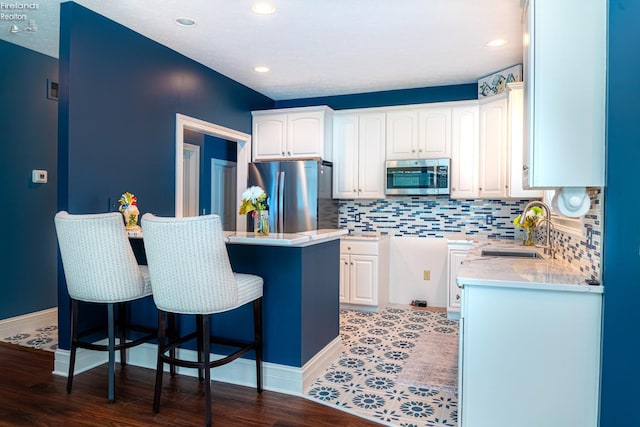 kitchen with a kitchen island, hardwood / wood-style floors, appliances with stainless steel finishes, sink, and white cabinetry