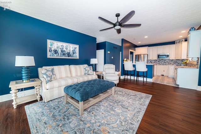 living room with ceiling fan, dark hardwood / wood-style flooring, and a textured ceiling