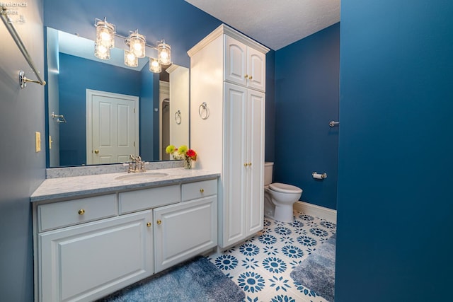 bathroom with a textured ceiling, vanity, and toilet