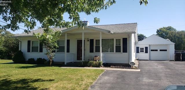 view of front facade with a garage, covered porch, an outbuilding, and a front yard