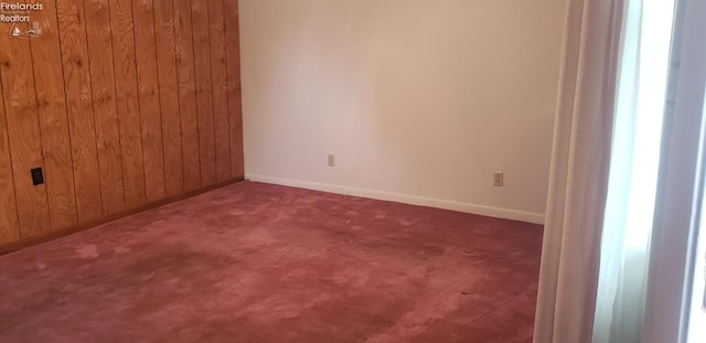 unfurnished room with wooden walls and carpet