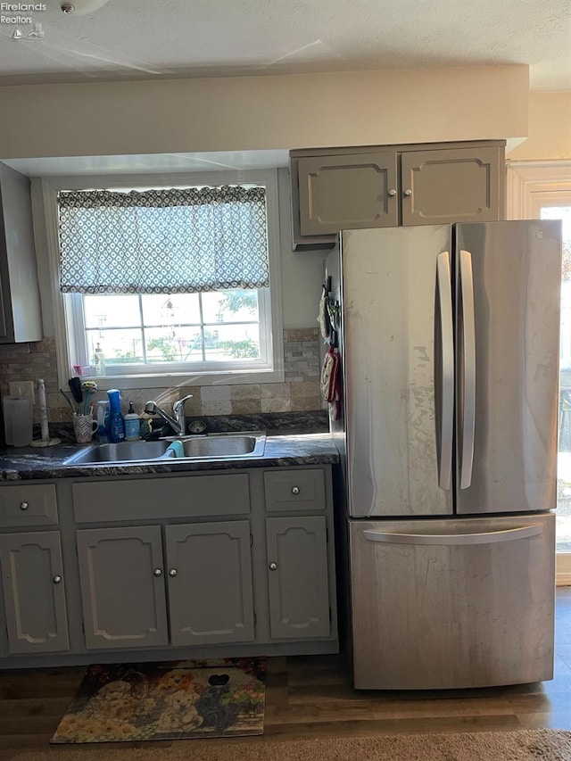 kitchen featuring sink, backsplash, gray cabinetry, dark hardwood / wood-style floors, and stainless steel refrigerator