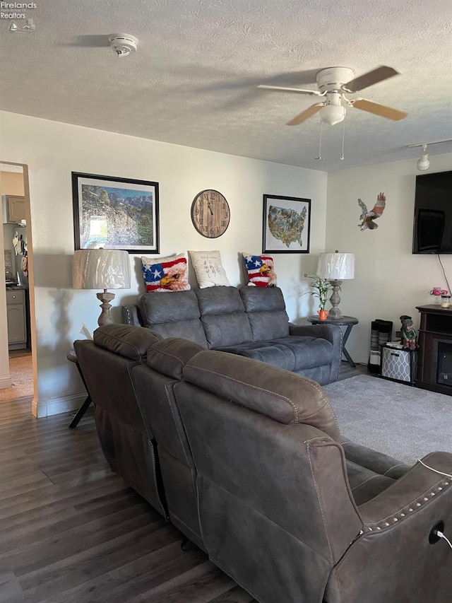 living room with ceiling fan, dark hardwood / wood-style flooring, and a textured ceiling