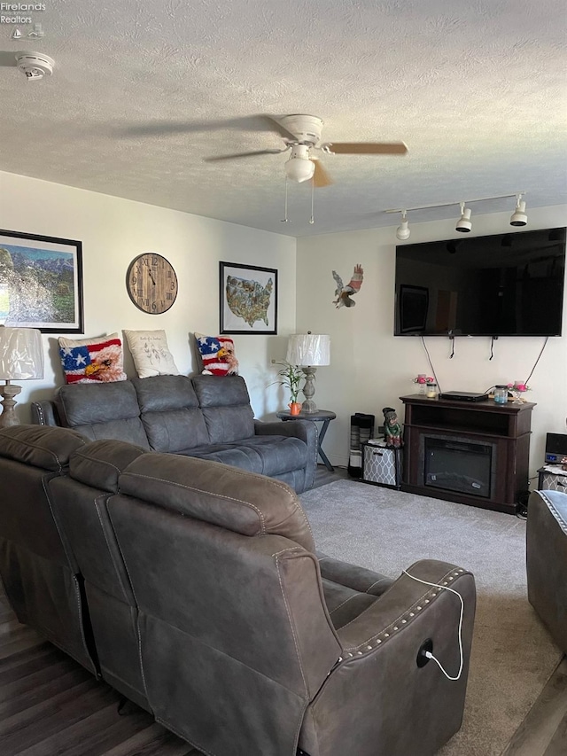 carpeted living room featuring ceiling fan and a textured ceiling