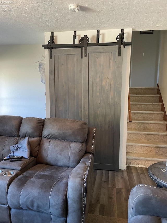 living room featuring dark hardwood / wood-style flooring, a barn door, and a textured ceiling