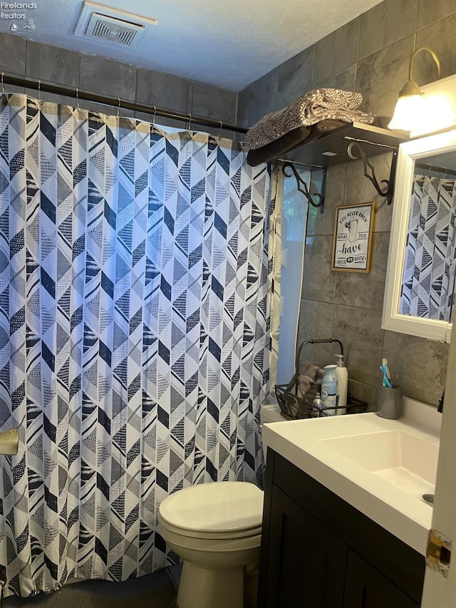 bathroom with tile walls, vanity, and toilet