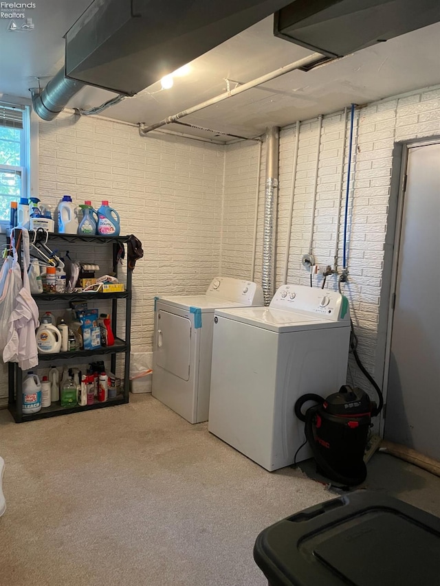 clothes washing area featuring washing machine and dryer and brick wall