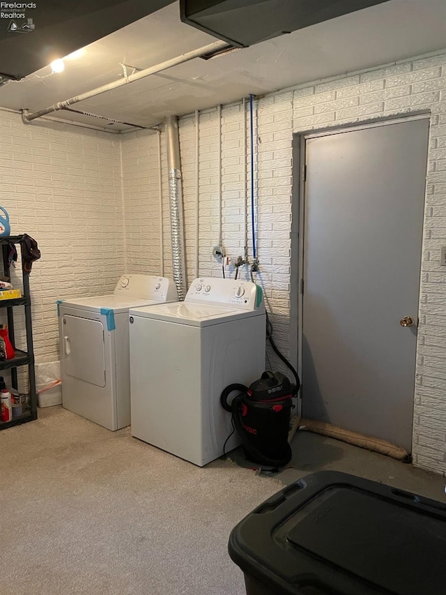 washroom with brick wall and washer and clothes dryer