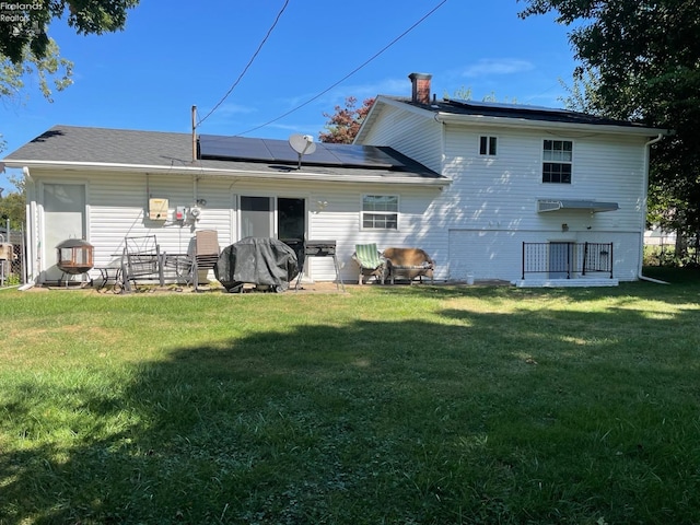 rear view of house with a yard and solar panels