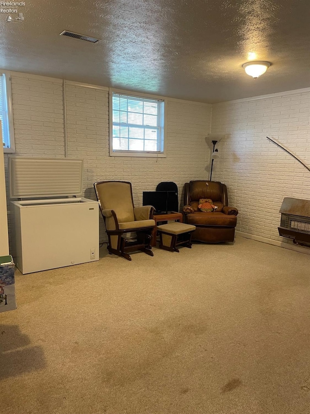 sitting room featuring carpet, a textured ceiling, and brick wall