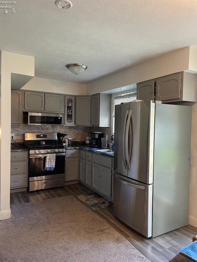 kitchen featuring gray cabinets, stainless steel appliances, backsplash, and dark hardwood / wood-style floors