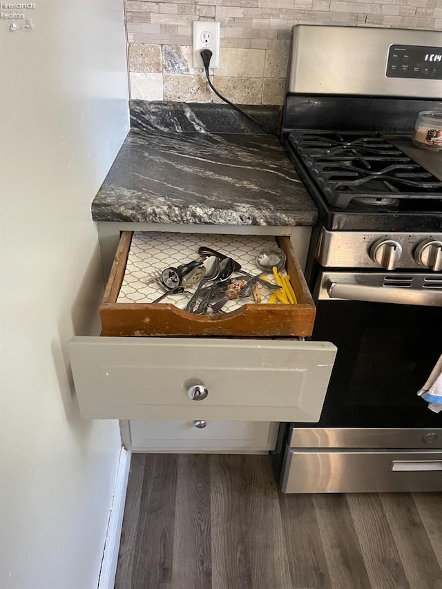 interior details featuring dark hardwood / wood-style flooring, tasteful backsplash, and stainless steel gas range oven