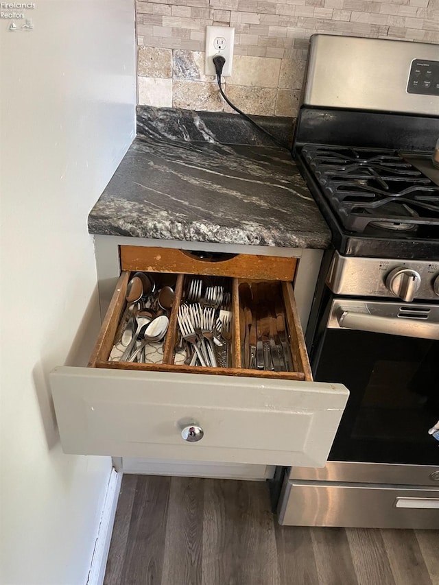 interior details with dark hardwood / wood-style floors, stainless steel gas stove, and tasteful backsplash