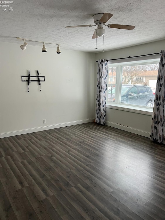 unfurnished room with ceiling fan, track lighting, dark wood-type flooring, and a textured ceiling