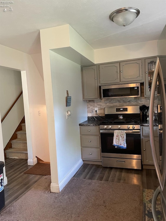 kitchen featuring dark wood-type flooring, stainless steel appliances, gray cabinetry, and decorative backsplash