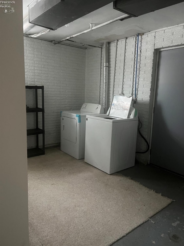 washroom with independent washer and dryer and brick wall