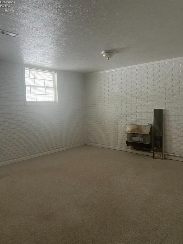 basement featuring brick wall, carpet floors, and a textured ceiling