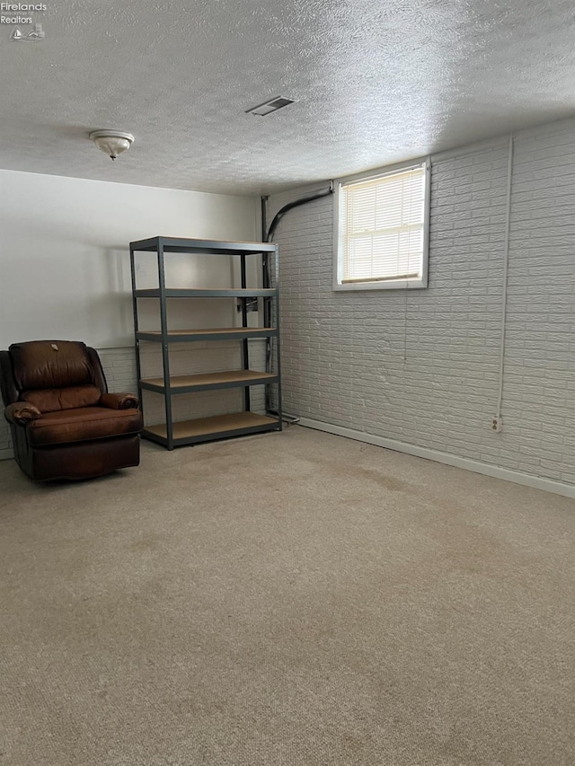 basement with brick wall, carpet floors, and a textured ceiling