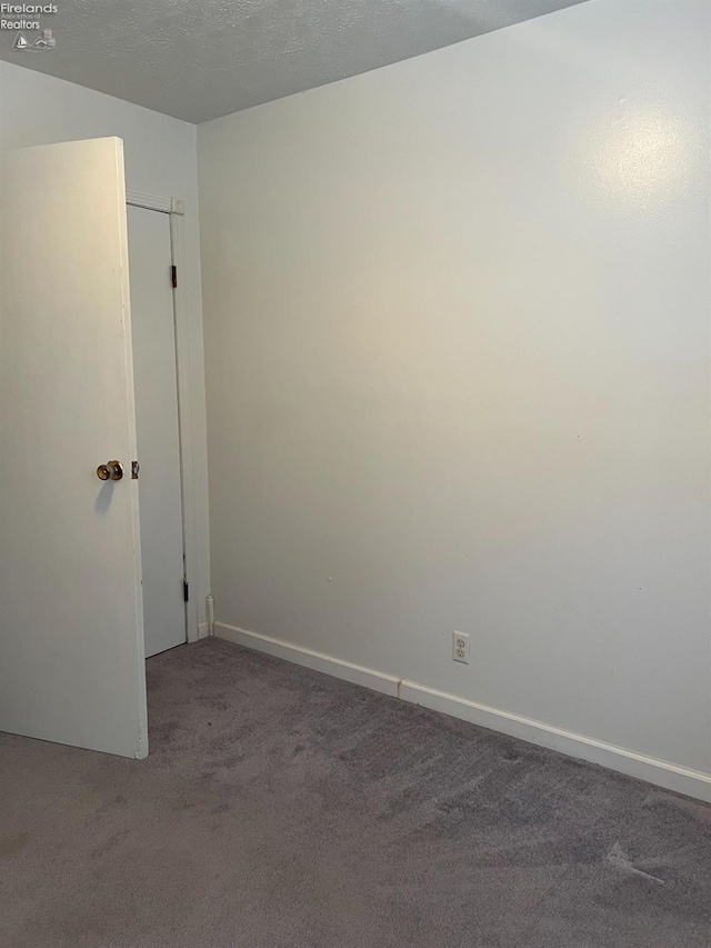 carpeted empty room with a textured ceiling