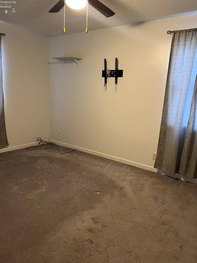 spare room featuring dark carpet and ceiling fan