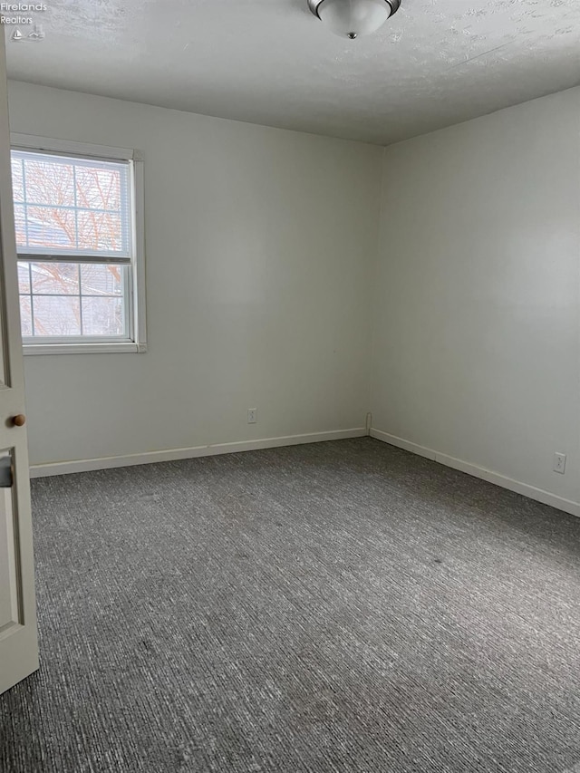 empty room with a textured ceiling and dark colored carpet