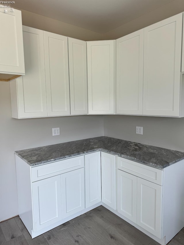 kitchen featuring white cabinets, dark hardwood / wood-style flooring, and dark stone counters