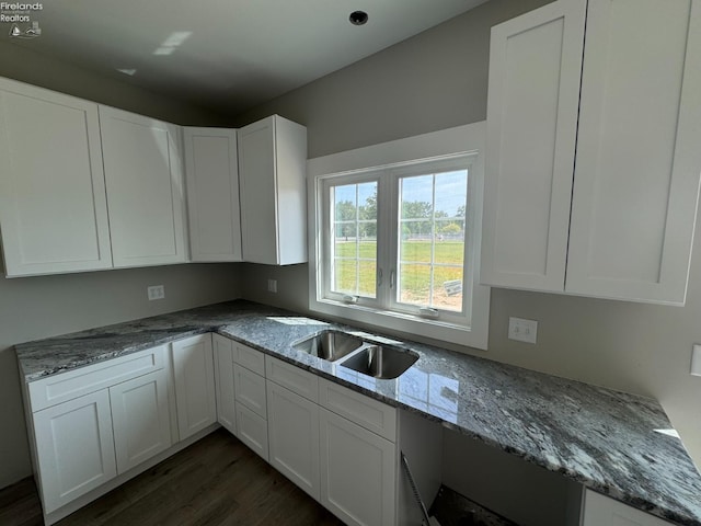 kitchen with stone counters, sink, white cabinets, and dark wood-type flooring