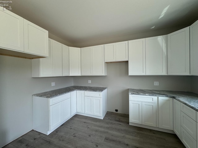 kitchen featuring hardwood / wood-style floors, white cabinetry, and dark stone counters