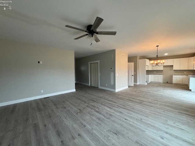 10 Eagle View Dr, Monroeville, OH 44847 - unfurnished living room featuring baseboards, a chandelier, ceiling fan, and light wood-type flooring