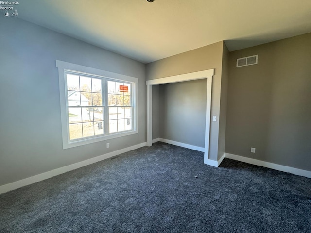 unfurnished bedroom with a closet and dark colored carpet