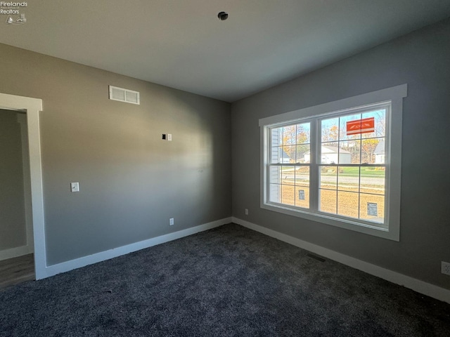 spare room featuring dark carpet