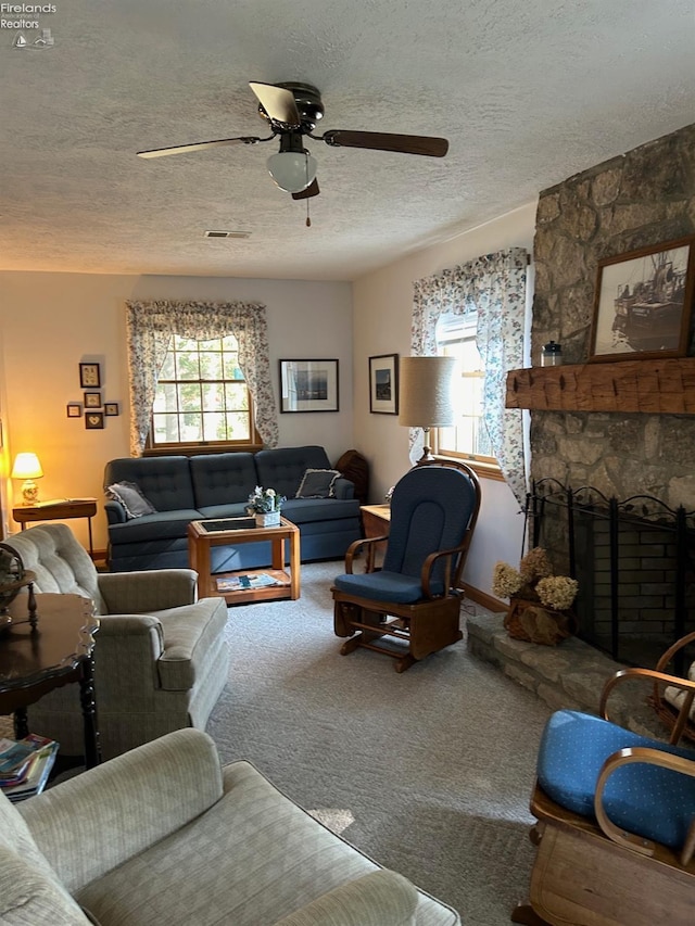 carpeted living area with a textured ceiling, a fireplace, visible vents, and ceiling fan