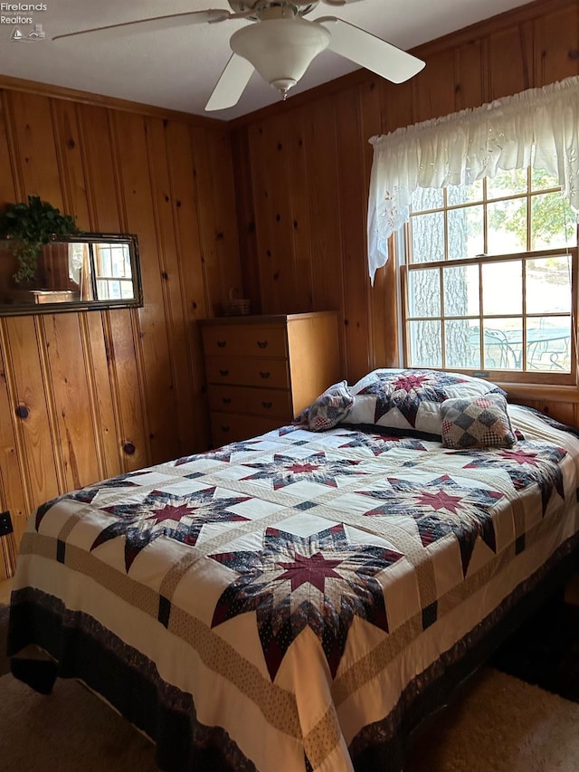 bedroom featuring wooden walls and ceiling fan