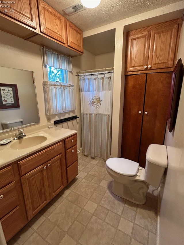 full bath with visible vents, a shower with curtain, toilet, a textured ceiling, and vanity