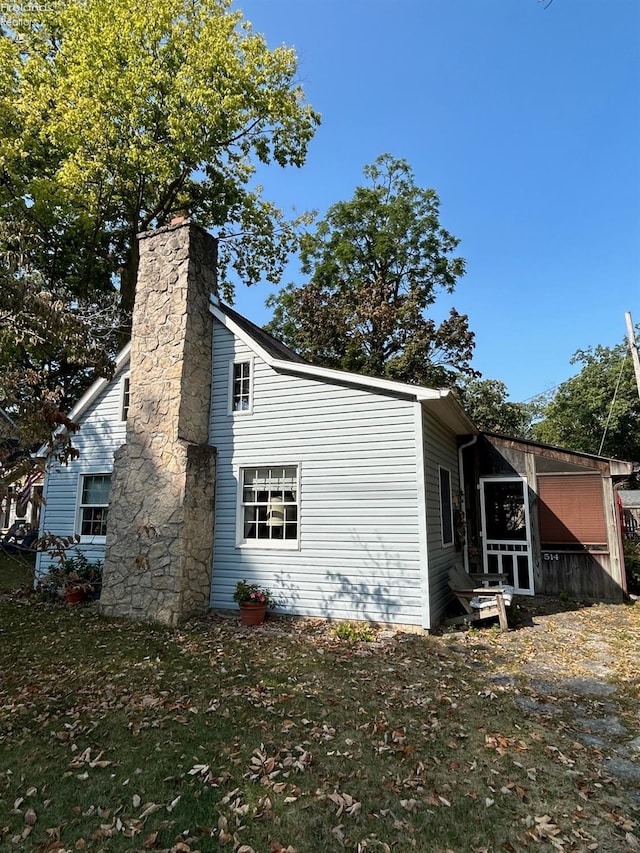 view of side of home with a yard and a chimney