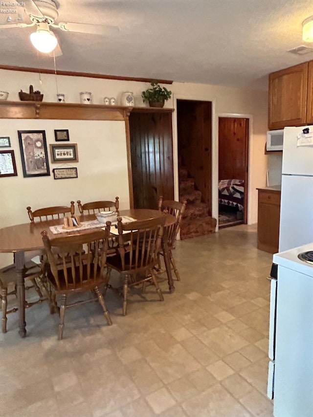 dining area featuring light floors, visible vents, ornamental molding, stairs, and ceiling fan