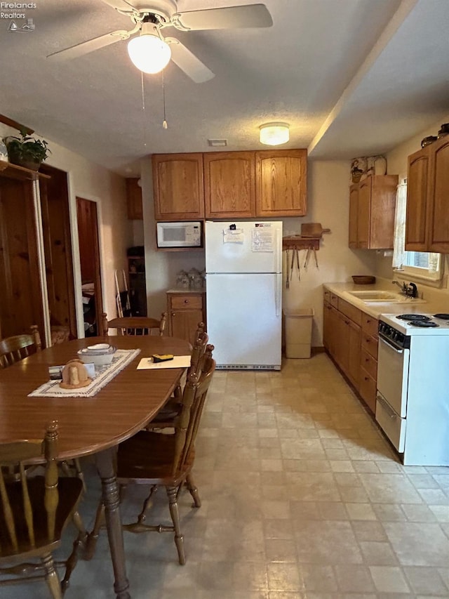 kitchen with white appliances, light floors, brown cabinets, and a sink