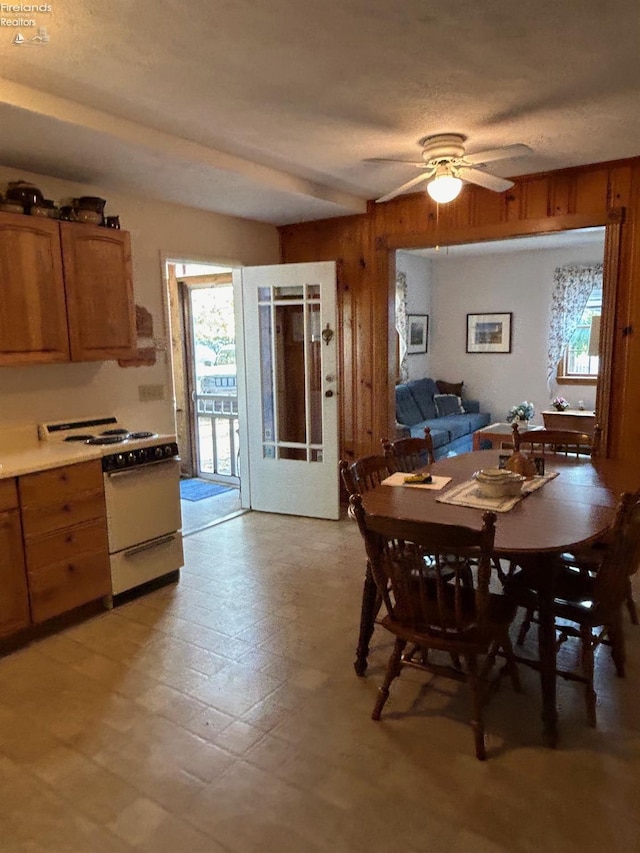 dining space with ceiling fan and wood walls