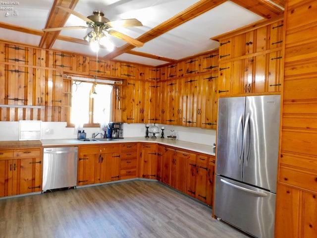 kitchen with wood walls, ceiling fan, light wood-type flooring, and appliances with stainless steel finishes