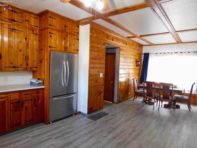 kitchen with light hardwood / wood-style flooring, ceiling fan, stainless steel fridge, and wooden walls