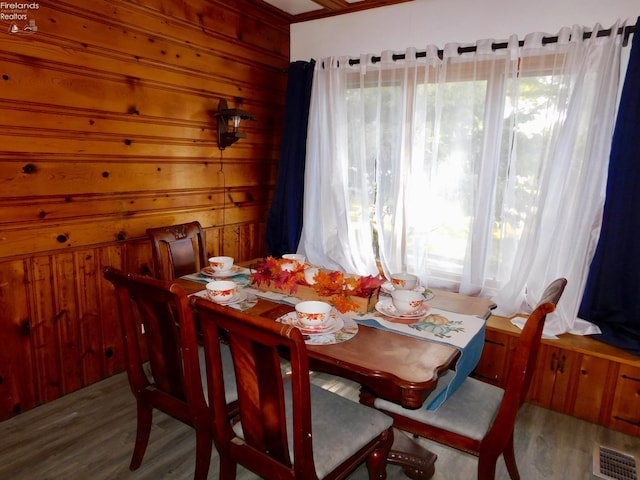 dining space with wooden walls and hardwood / wood-style flooring