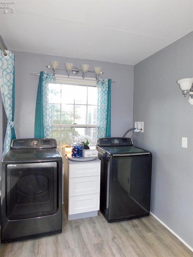 clothes washing area with light hardwood / wood-style flooring and washer and dryer