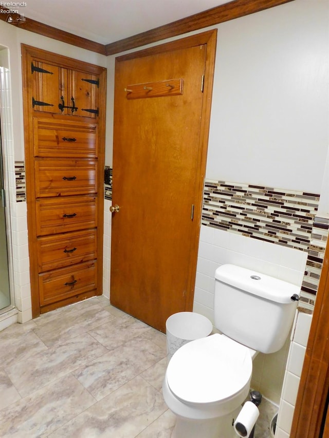 bathroom with a shower with door, tile walls, toilet, and crown molding